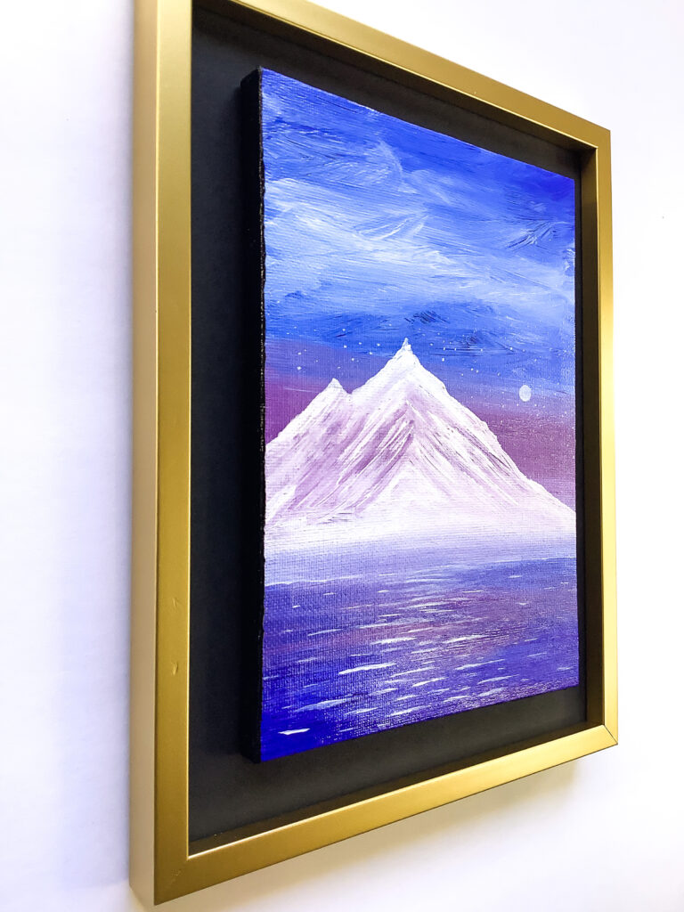 Painting side view of glimmering water sitting below a magnificent violet snow-capped mountain, a vibrant blue sky looms overhead.